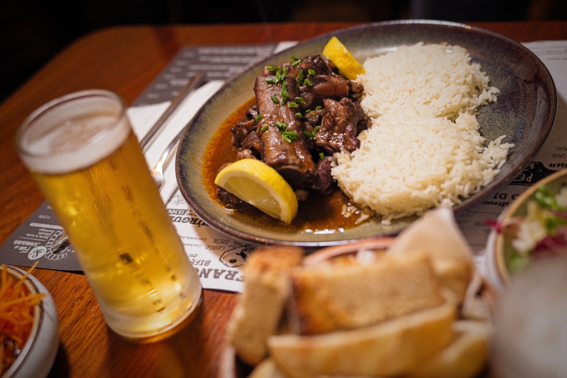 Prato de carne estufada com arroz branco e limão, acompanhado de cerveja.